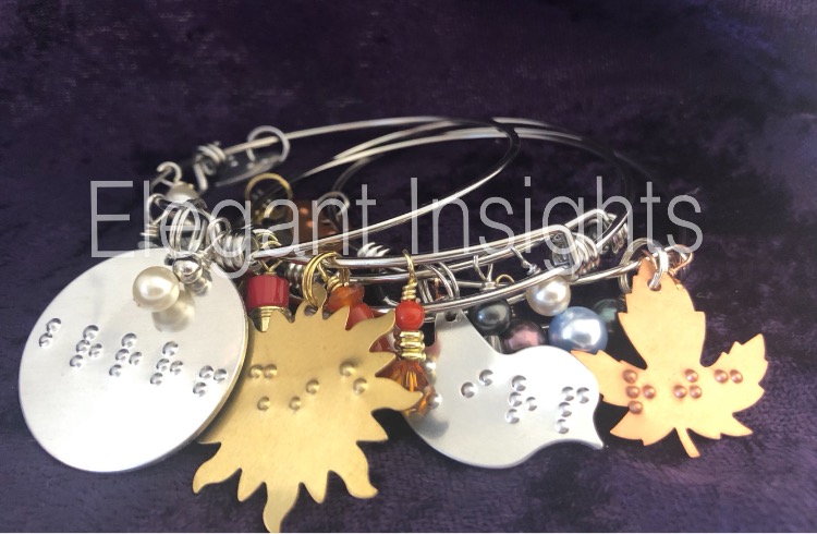 Photo of a grouping of four bracelets. They are called the Charmed by the Seasons Expandable Dangle Bangle Bracelets, and they are arranged in order from left to right: winter, summer, spring, fall.