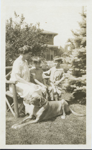 Helen Keller seated on a bench with two unidentified boys and her dog Hans in her Forest Hills garden, Queens, circa 1920s