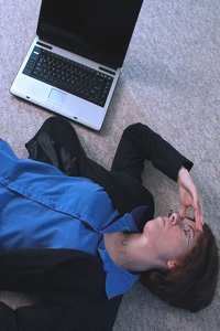A woman lies on the floor next to her laptop, frustrated with her web experience.
