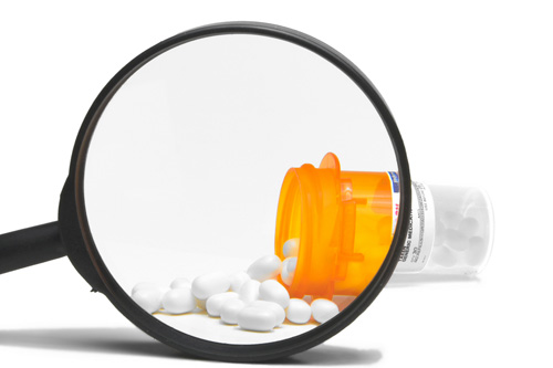 Prescription medication, shown through a magnifying glass.