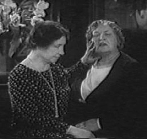 This still picture is taken from the 1953 movie Helen Keller in Her Story. It shows Helen with her fingers pressed against Anne's right cheek and neck, illustrating the Tad-Oma method of speech training.