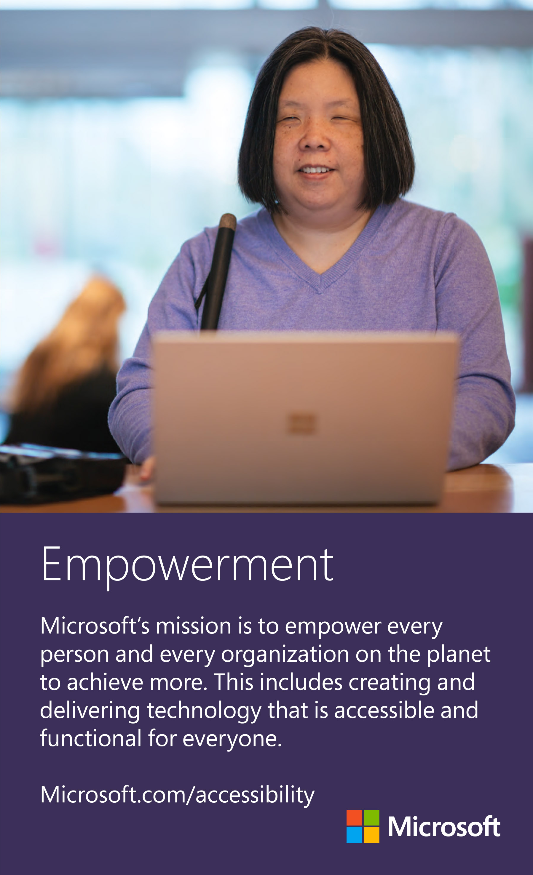Image: A middle-aged Asian woman with blindness smiles while using a laptop computer.