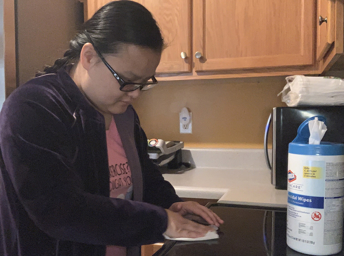 An Asian woman disinfects a countertop.