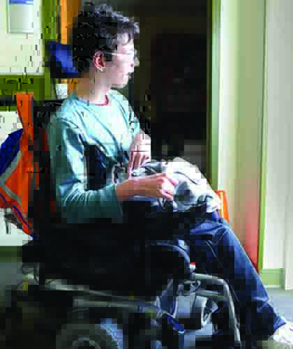 A White young man in a wheelchair looks out a sunny window.