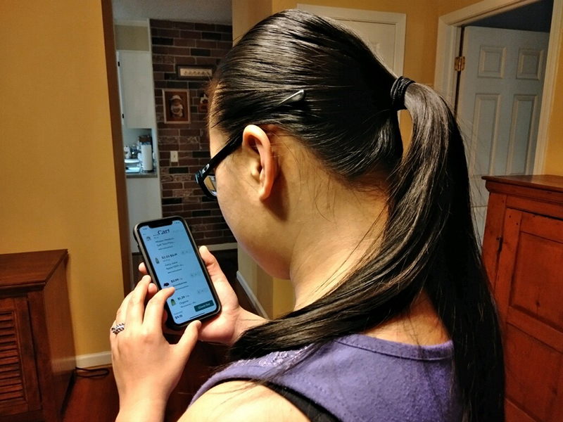 An Asian woman uses a smartphone to order groceries.