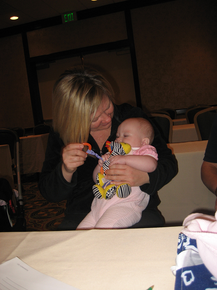 A White infant girl and her White mother play with a black and white crinkle toy.