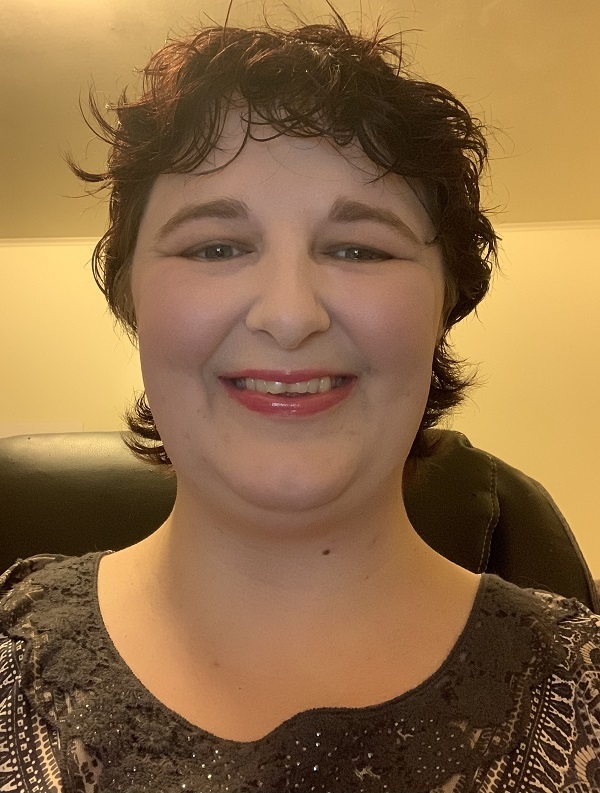 Dr. Carlie Rhoads, seated and smiling, short dark hair and green eyes.