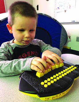 A 4-year old preschool boy presses on the keys of the APH Braille Bug. 