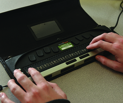 A photo of light skinned hands on a braille notetaking device