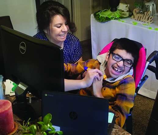 A Hispanic high school student who is deafblind and his mother smile as they work on number recognition with his TVI via Zoom. 