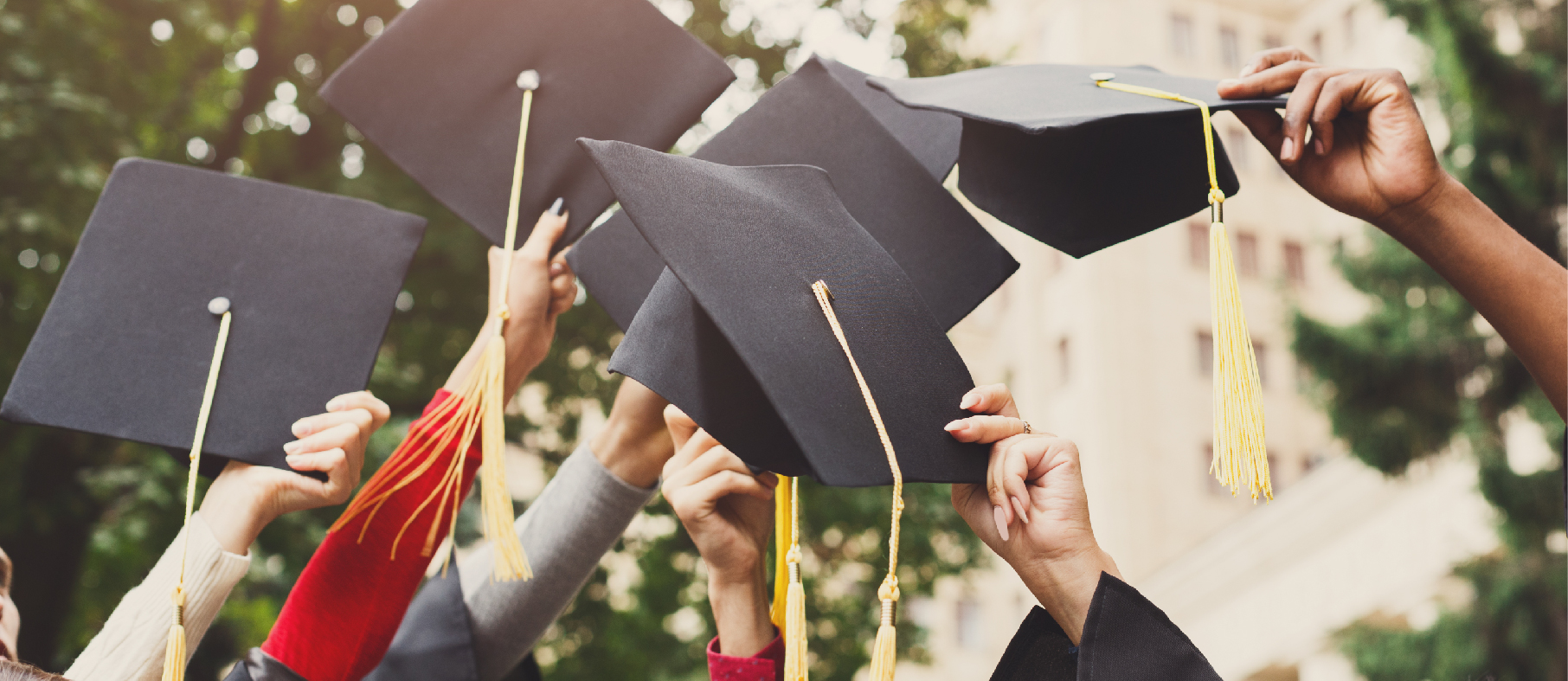 Graduating students wave their graduation caps in the air.