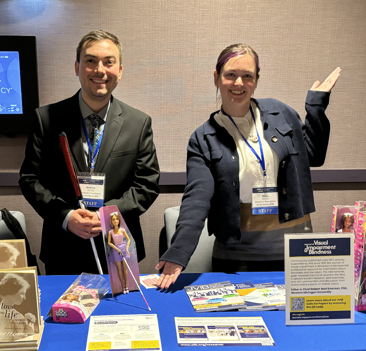 Two smiling AFB employees stand at the AFB exhibit table.