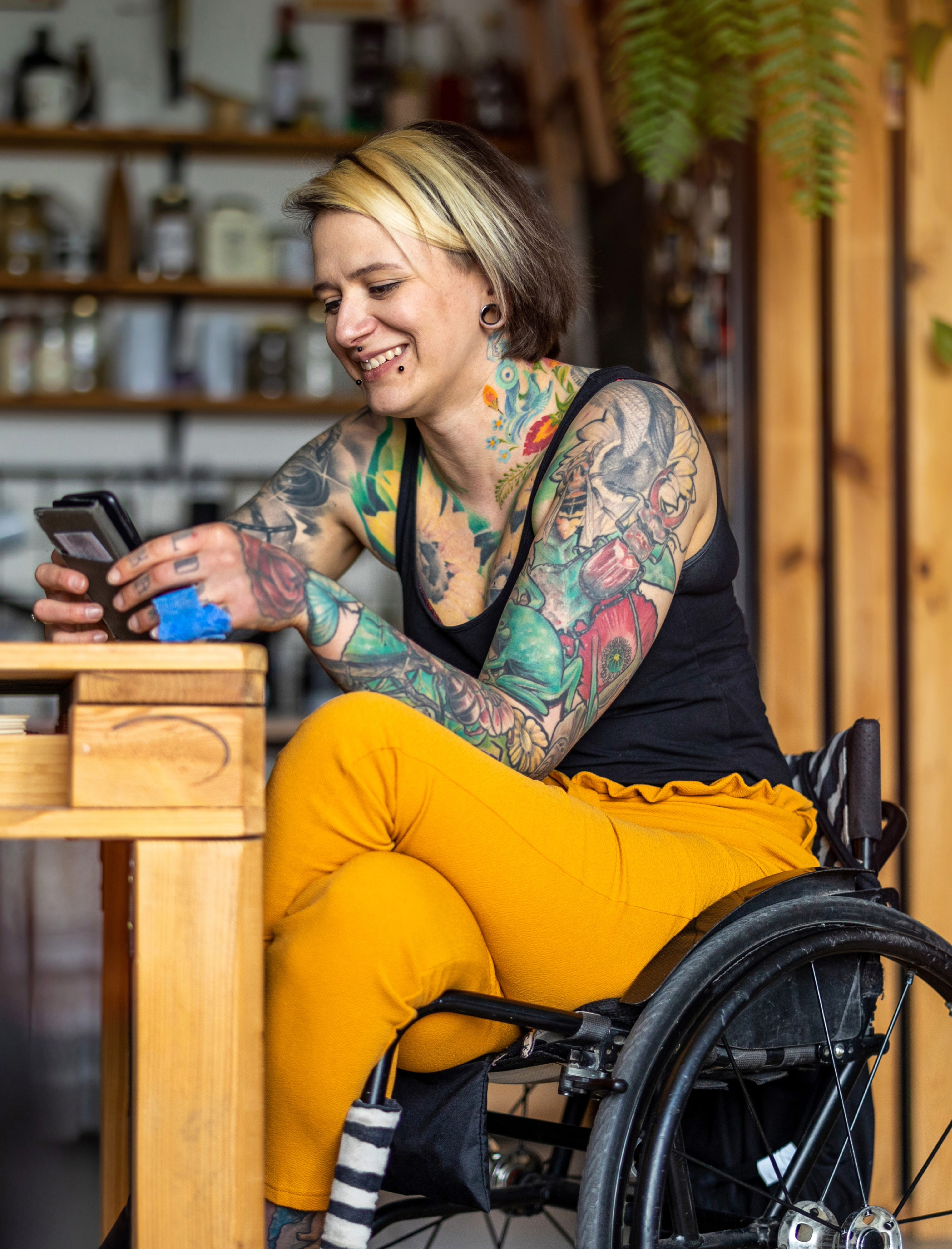 A woman in a wheelchair smiles as she uses her phone.