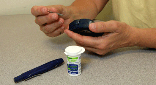 a person's hands inserting a testing strip into a blood glucose meter