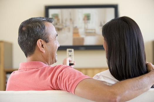 Asian couple smiling while watching TV