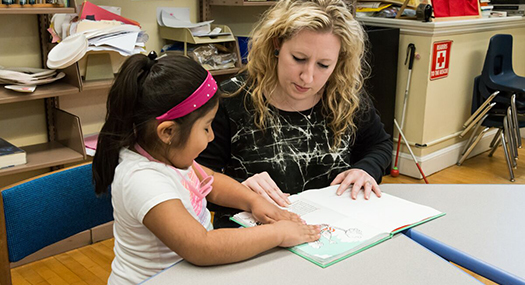 A teacher and her student, who is practicing reading braille