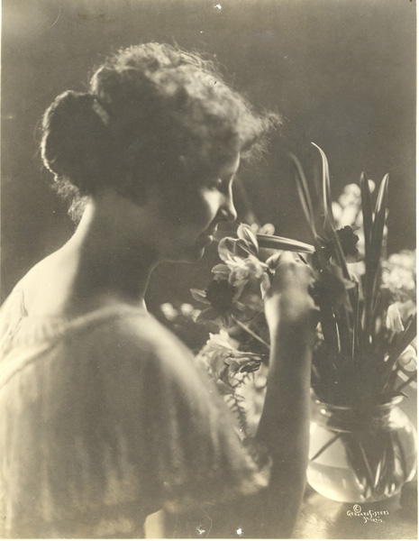 Helen Keller smelling flowers in a vase, circa 1919