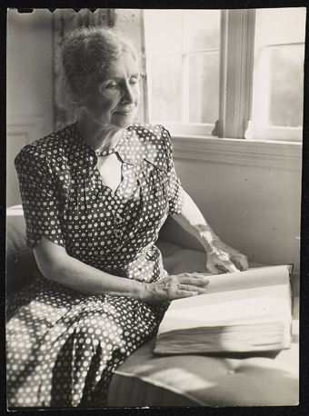 Helen Keller reading a book in braille
