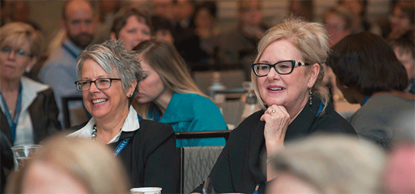 two women smiling as they listen to an AFBLC17 speaker