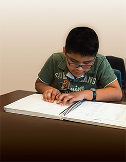 Young boy sitting at desk using a tactile map