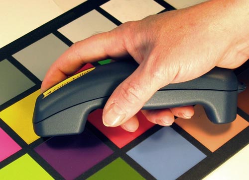 The Color Teller being held against a colored square on a color chart.