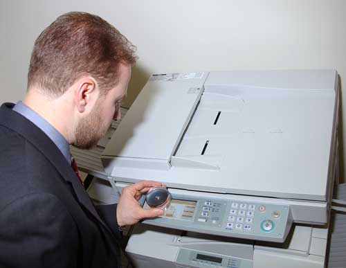 Man using a magnifier to look at the touch screen on a copy machine.