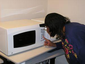 A woman leaning over the controls of the GE microwave.