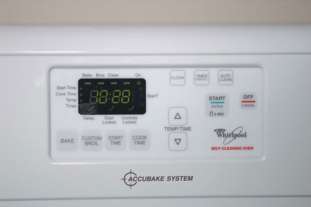 Closeup photo of oven touch pad controls showing a display screen for time or temperature and flat buttons, some with texture.