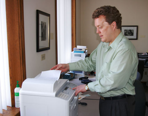 Photo of a man feeding a sheet of paper into the Samsung copier and pressing a button.