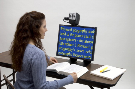 A young woman reading a book in high-contrast yellow letters on a blue background.