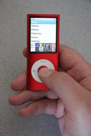 A person's hand operating an iPod Nano. The menu shows that Music has been selected.
