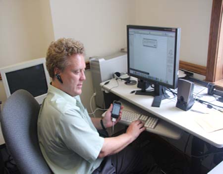 The author is listening to the iPhone's speech output with a wireless device, while he performs a sync operation