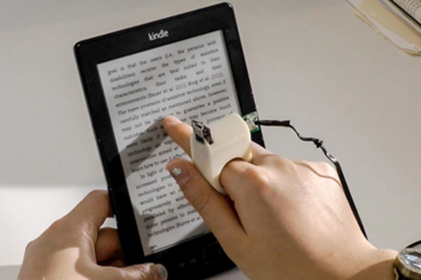 Photo of the Finger Reader reading text from a Kindle's screen.