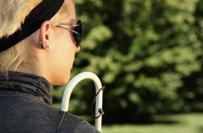 Profile of a blind white woman holding a cane