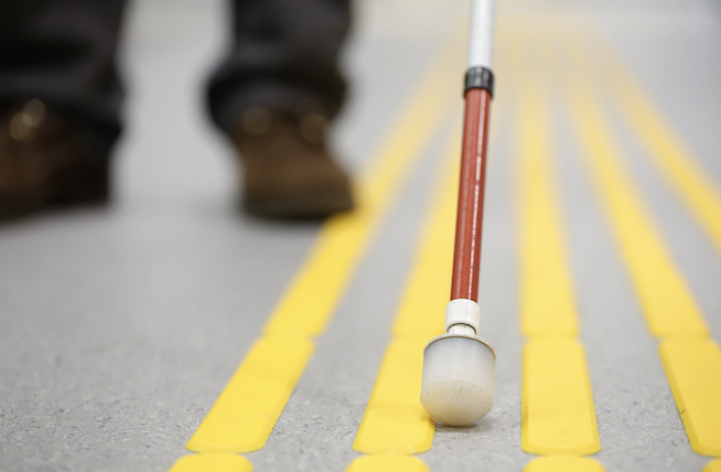 Blind pedestrian walking on tactile paving.