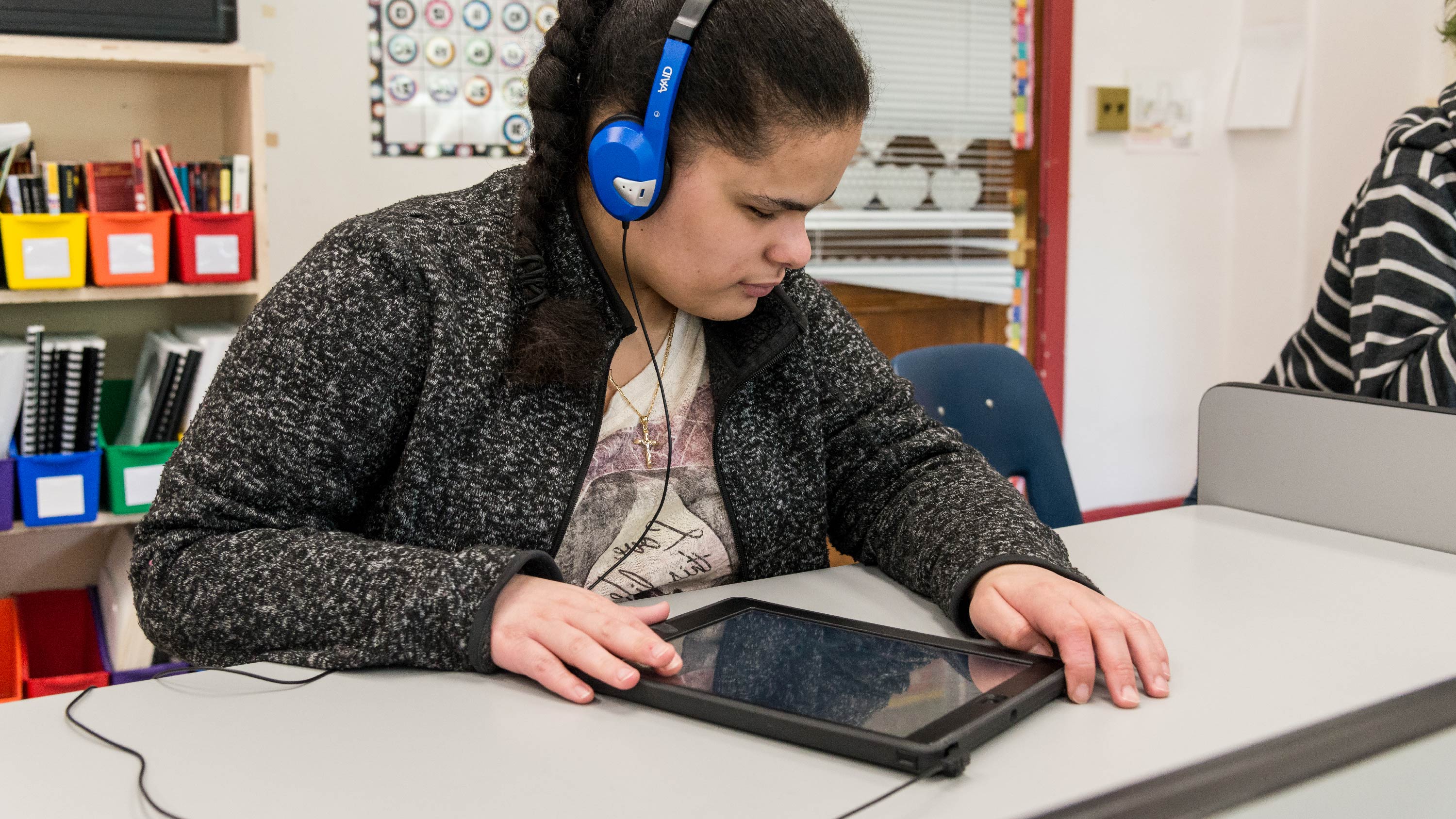 A student wearing headphones using a screen reader on her iPad