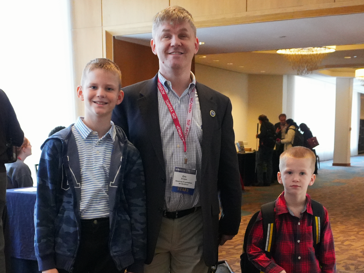 A father smiles with his two sons at an AFB event.